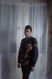 a black woman standing in a room with curtains